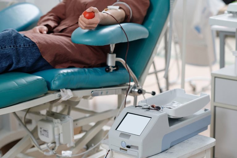 unrecognizable donor relaxing on procedure chair during blood transfusion